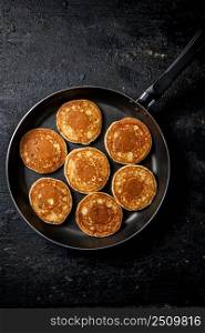 Homemade pancakes in a frying pan. On a black background. High quality photo. Homemade pancakes in a frying pan. 