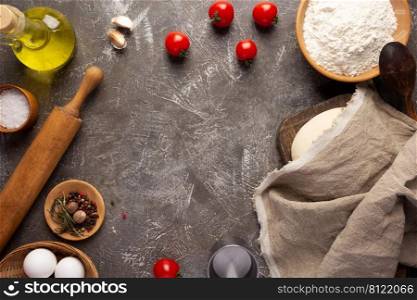Homemade pizza and flour with ingredients at table. Dough for pizza on tabletop background. Recipe concept in kitchen