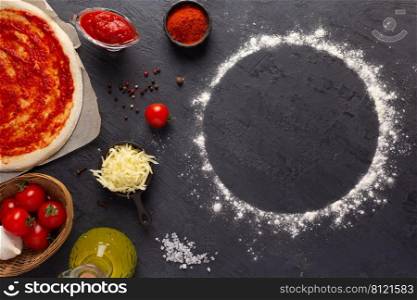 Homemade pizza and sauce with ingredients at table. Dough for pizza on tabletop background. Recipe concept in kitchen