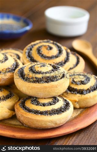 Homemade poppy seed rolls piled on a plate, photographed with natural light (Selective Focus, Focus one third into the roll on the top)