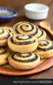 Homemade poppy seed rolls piled on a plate, photographed with natural light (Selective Focus, Focus one third into the roll on the top)
