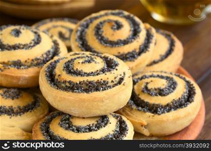 Homemade poppy seed rolls piled on a plate, photographed with natural light (Selective Focus, Focus one third into the roll in the front)