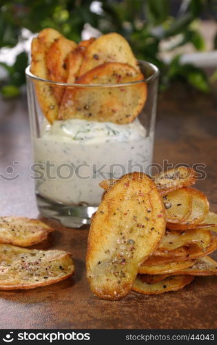 Homemade potato chips and spicy dip served in glass.