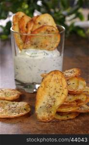 Homemade potato chips and spicy dip served in glass.