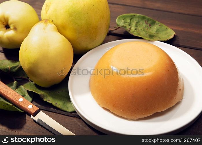 Homemade quince jelly and fruits on wooden background. Sweet food