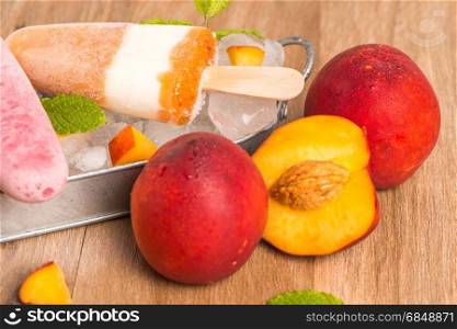 Homemade raspberries and peach popsicles on a wooden table.
