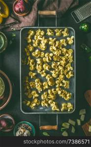Homemade raw vegetarian tortellini pasta in metal tray on dark rustic kitchen table background with ingredients and utensils, top view. Cooking preparation. Italian food