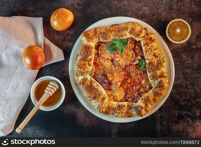 Homemade red blood orange galette with mint and honey. Fruit bakery. Healthy vegetarian dessert. Open pie, orange tart. Top view