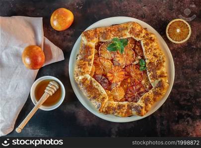 Homemade red blood orange galette with mint and honey. Fruit bakery. Healthy vegetarian dessert. Open pie, orange tart. Top view