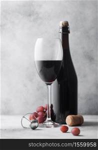 Homemade red wine in bottle with crystal glass corks with vintage corkscrew and grapes on light table background.