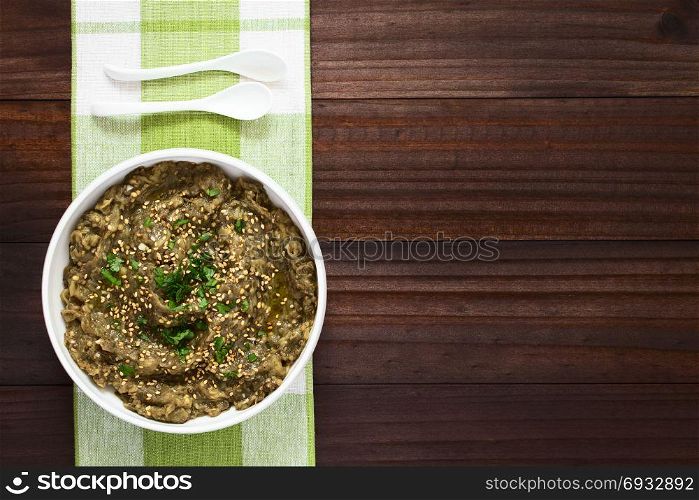 Homemade roasted eggplant dip or spread, baba ganoush in the Mediterranean cuisine, with olive oil, sesame and parsley on top, photographed overhead with natural light. Roasted Eggplant Dip or Spread