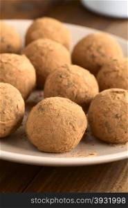 Homemade rum balls covered with cocoa powder, photographed with natural light (Selective Focus, Focus on the first ball)