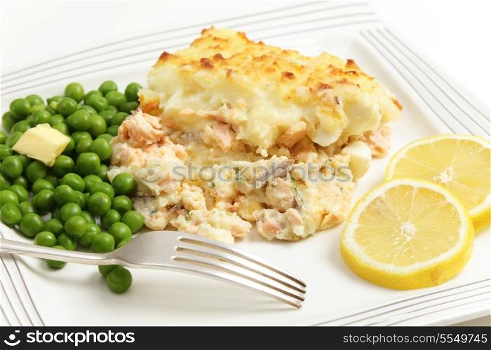 Homemade salmon, egg and potato pie, served with boiled peas and garnished with slices of lemon