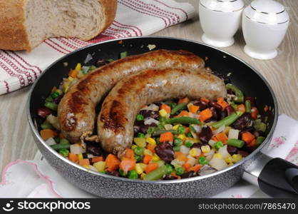 Homemade sausages with vegetables in a pan