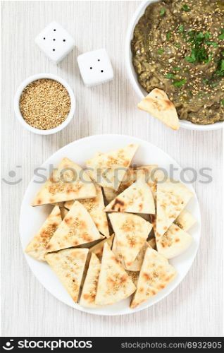 Homemade sesame pita chips with roasted eggplant dip or spread, baba ganoush in the Mediterranean cuisine on the side, photographed overhead with natural light. Sesame Pita Chips with Roasted Eggplant Dip