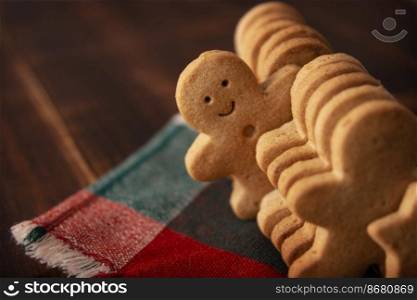 Homemade smiling gingerbread man cookie peeking out from a row of cookies. Standing out from crowd concept