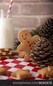 Homemade smiling gingerbread man cookie peeking out from behind a pinecone. These cookies are traditionally made in the holiday season for Christmas.
