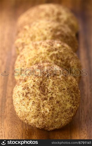 Homemade snickerdoodle cookies with cinnamon and sugar coating on wooden plate, photographed with natural light (Selective Focus, Focus in the middle of the first cookie)