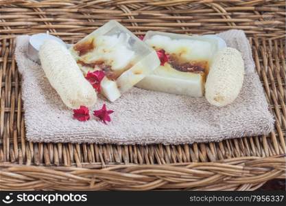 Homemade soap and luffa on towel in rattan basket