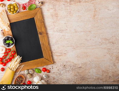 Homemade spaghetti pasta with quail eggs and charcoal menu board and cheese on wood background. Classic italian village food. Garlic, champignons, black and green olives, wooden spatula.