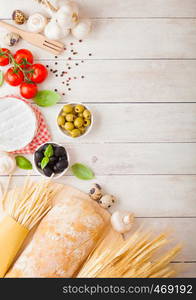 Homemade spaghetti pasta with quail eggs with bottle of tomato sauce and cheese on wood background. Classic italian village food. Garlic, champignons, black and green olives, bread and wheat