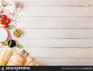 Homemade spaghetti pasta with quail eggs with bottle of tomato sauce and cheese on wood background. Classic italian village food. Garlic, champignons, black and green olives, bread and wheat