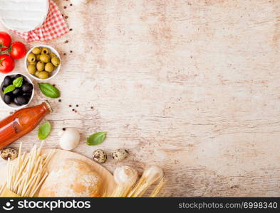 Homemade spaghetti pasta with quail eggs with bottle of tomato sauce and cheese on wood background. Classic italian village food. Garlic, champignons, black and green olives, oil and bread.