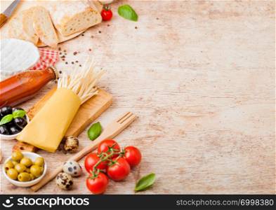 Homemade spaghetti pasta with quail eggs with bottle of tomato sauce and cheese on wood background. Classic italian village food. Garlic, champignons, black and green olives, bread and spatula.