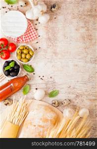 Homemade spaghetti pasta with quail eggs with bottle of tomato sauce and cheese on wood background. Classic italian village food. Garlic, champignons, black and green olives, oil and bread.