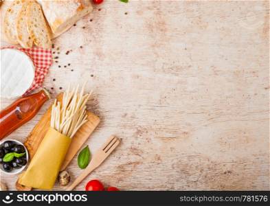 Homemade spaghetti pasta with quail eggs with bottle of tomato sauce and cheese on wood background. Classic italian village food. Garlic, champignons, black and green olives, bread and spatula.