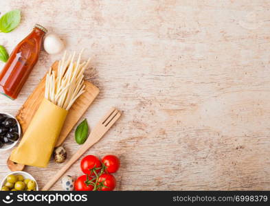 Homemade spaghetti pasta with quail eggs with bottle of tomato sauce on wood background. Classic italian village food. Garlic, champignons, black and green olives.