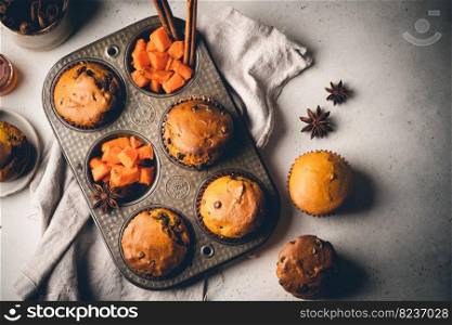 Homemade spicy pumpkin muffins or cupcakes with chocolate on a metal rack, top view. Autumn dessert. Selective focus. spicy pumpkin muffins