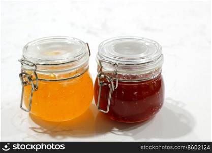 homemade strawberry and pineapple jam in jars on white table for breakfast