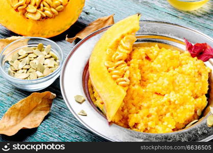 Homemade tasty porridge with orange pumpkin on rustic background.Healthy autumn breakfast.. Autumn porridge with pumpkin