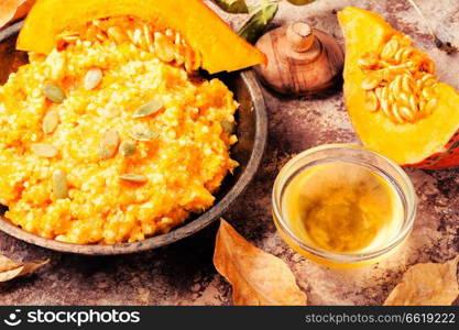 Homemade tasty porridge with orange pumpkin on rustic background.Healthy vegetarian meal.. Autumn porridge with pumpkin