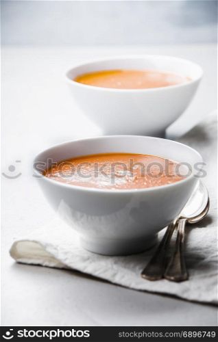 Homemade tomato cream soup in bowls (or gazpacho) over concrete background