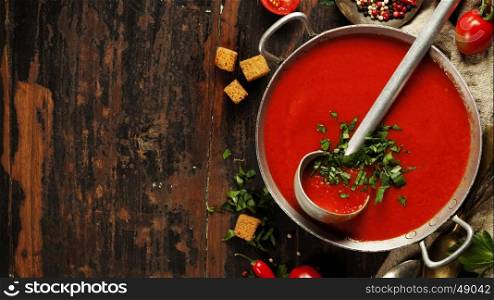 Homemade Tomato soup on wooden table, top view