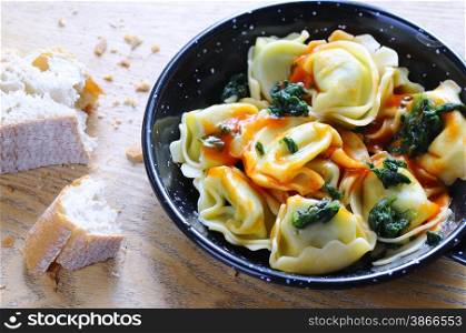 Homemade tortellini with spinach on wooden table.