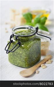 Homemade traditional basil pesto and ingredients on a rustic wooden table