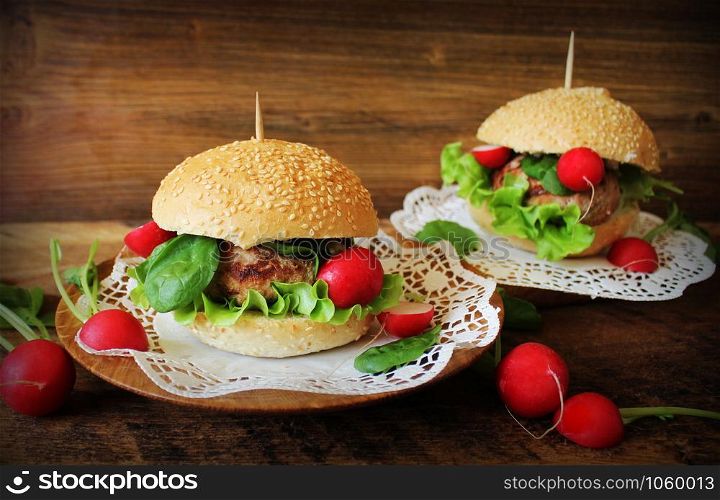 Homemade traditional burgers with beef,radish,lettuce, spinach , served on wooden background. Fast food. Homemade traditional burgers with beef,radish,lettuce, served on wooden background.