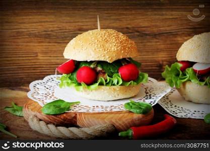 Homemade traditional burgers with beef,radish,lettuce, spinach , served on wooden background. Fast food. Homemade traditional burgers with beef,radish,lettuce, served on wooden background.