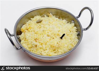 Homemade traditional saffron rice, made with basmati long-grain rice, cardamom pods, cloves and saffron threads, in an Indian kadai or karahi (wok) bowl