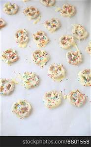 Homemade white chocolate-covered pretzels with colorful sprinkles and copy space