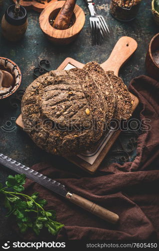 Homemade whole grain bread on cutting board with knife. Top view