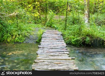 Homemade wooden bridge over a small river forest