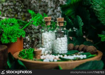 Homeopathic globules in small bottles with fresh leaves, homeopathy concept 