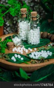 Homeopathic globules in small bottles with mint leaves, homeopathy concept