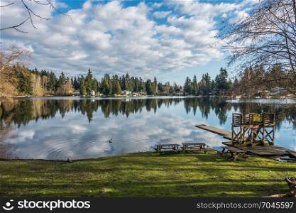 Homes, trees and sky are reflected in the water of Mirror Lake in Federal Way, Washington.