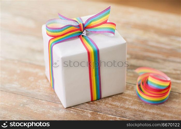 homosexual and lgbt concept - close up of gift box with gay pride awareness ribbon on wooden table at home. close up of gift box with gay awareness ribbon. close up of gift box with gay awareness ribbon