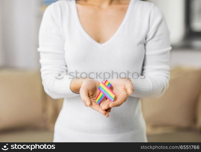 homosexual and lgbt concept - close up of woman holding gay pride awareness ribbon. close up of woman holding gay awareness ribbon. close up of woman holding gay awareness ribbon